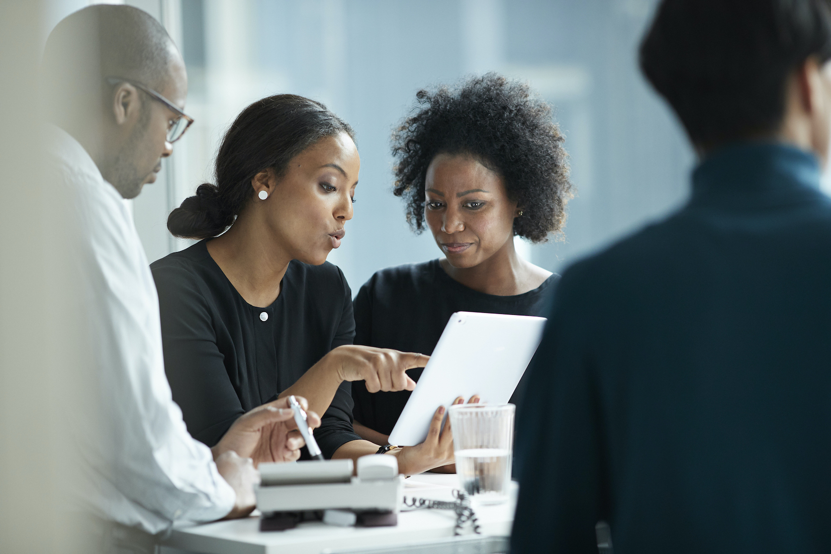 group of co workers standing around desk and having meeting